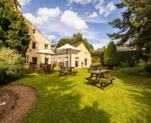 An external garden view of the Alston House Hotel  with outdoor seating on a lawned area.