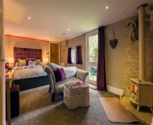 An internal view of a large bedroom   with external access and a wood burner in the five-star  Aphrodites Boutique Hotel near Bowness-on-Windermere