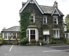 An image of the four-star Glencree Bed and Breakfast, a stone faced detached property with parking a conservatory on the side.