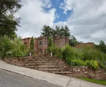 An external image of the three-star Heather Glen Country House,  a stone built property with a distinctive reddish hue.
