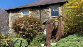 An exterior image of the four-star Ivythwaite Lodge Guest House with front garden and a house of traditoinal Lakeland stone
