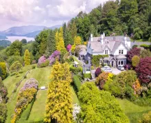 A beautiful image of the five-star Lindeth Fell Country House, elevated over Lake Windermere with well tendered gardens and fell views