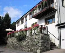 An external image of the white rendered Lingwood Lodge, over two fllows and a blcony on the upper floow. Flower boxes adorn the property making give a welcoming impression.