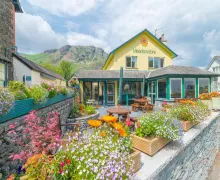 A view of the 3 star Meadowdore Cafe B&B in Coniston with scenic fells in the background.