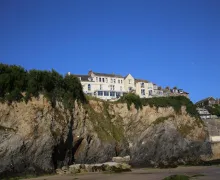 A white painted hostel perched on the cliftop in Newquay with panoramic views from seaward rooms