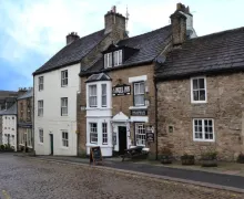 An external image of the three-star Angel Inn with a cobbles street  in the small town of Alston