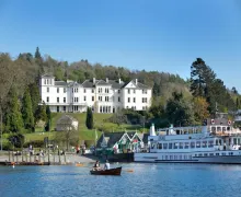An impressive view of the 4 star  Belsfield Hotel slightly elevated over Lake Windermere with boats in the foreground.