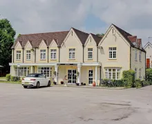 An external view of  The three star Gables Hotel Birmingham Airport with large parking area.