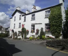 An image of the large 3 story, and four-star Virginia Cottage Guest House in Bowness-on-Windermere with a splash of color from the flowers in  Window boxes and Hanging baskets.