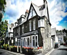 An exterior view of the  Windermere Lynwood Guest House  with flower's adorning the wall  close to the town in the Lake District.