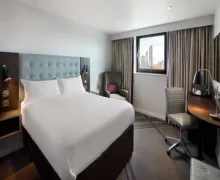 An internal view of Premier Inn London Blackfriars Fleet Street Bedroom, with two chairs , a desk and plus a TV and en-suite bathroom out of view.