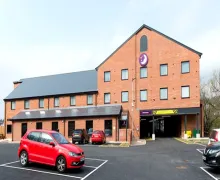 A view of the three-star, three-story Premier Inn Ulverston, featuring a gable on the right-hand side with reception below. The car park is immediately in front of the property.